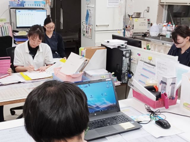 スタッフが働く様子の事務室 スタッフイメージ スタッフが事務作業をしている落ち着いた空間です。デスク上には必要な資料が整っております。