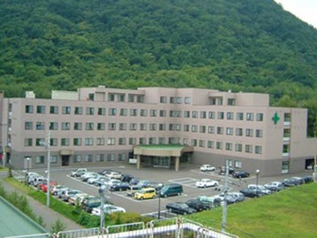 施設外観 外観   山の緑を背景にした落ち着いた建物で、正面には車寄せと駐車場が見えます。就業先の雰囲気を外から確認したい方に分かりやすい外観です。