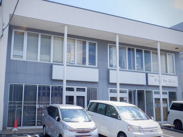 二階建ての建物外観 外観 明るい光が差し込むシンプルな二階建てです。駐車スペースには複数の車が停められます。