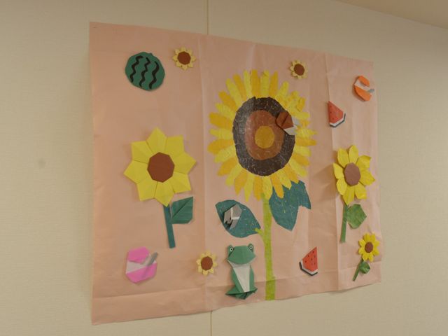 壁に飾られた手作り絵画 掲示物 壁に飾られた明るい手作りの絵画が、楽しいアート活動の一環である様子を伝えています。