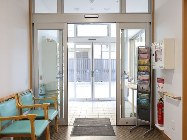エントランスの待合室風景 玄関 広くて明るいエントランスは、待合い席も備えており、来訪者を心地よくお迎えします。安全に配慮した設備も整っており、安心してご就業いただける環境です。