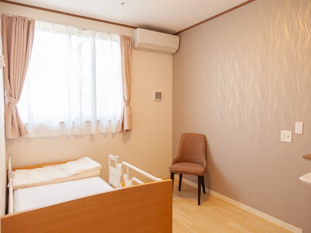 居室のベッドと椅子 居室 ゆったりとした雰囲気の個室です。ベッドと椅子があり、くつろぎながらプライベートな時間を過ごせます。