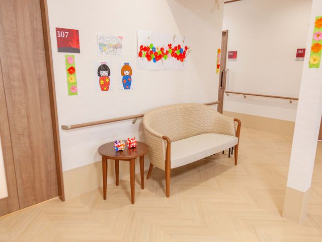 廊下に設置された安全ベンチ 廊下 手すり沿いに配された安全な休憩スペースは、居心地の良い時間を過ごせる設計です。壁に飾られた作品も温かな雰囲気を醸し出しています。
