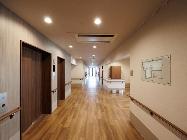 広々とした綺麗な廊下 廊下 明るく広々とした廊下は、木目調の床と清潔感あふれる壁面で、訪れる人にやすらぎを提供します。手すりが整備され、安全に配慮された設計となっています。
