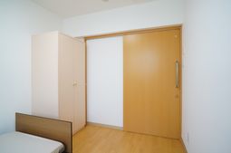 シンプルな居室の扉とベッド