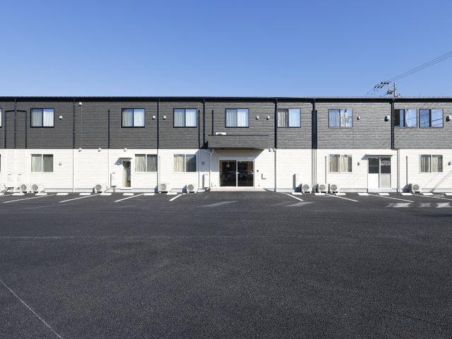 明るい施設の正面外観 外観 広々とした駐車スペースがあり、すっきりとしたデザインの建物で、快適な環境が整っています。