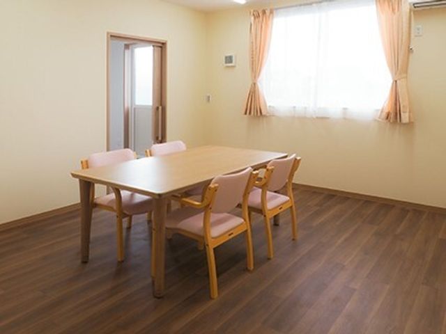 シンプルな共有ダイニング 相談室 ゆとりあるダイニングでは、共に食事を楽しむ穏やかな時間を提供しています。明るい窓辺で、ひとときの安らぎを得られる空間です。