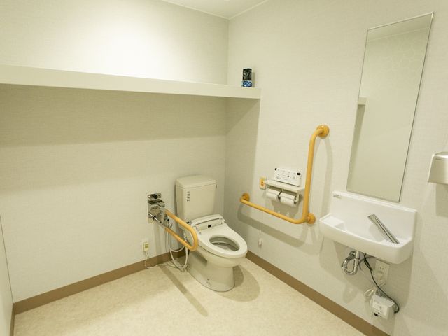 バリアフリーなトイレ設備 トイレ 安全に配慮された手すり付きのトイレです。利用者の快適さと安心感を重視したデザインになっています。