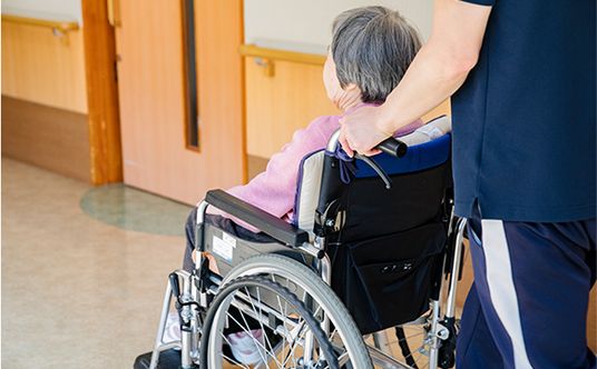 車椅子の人とスタッフの廊下  
