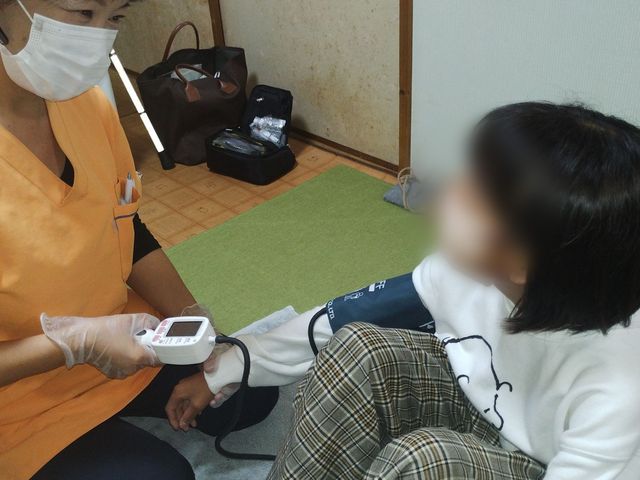 体調確認の様子 スタッフイメージ 医療スタッフが健康チェックを行う場面です。丁寧にサポートしながら働く姿を見られます。