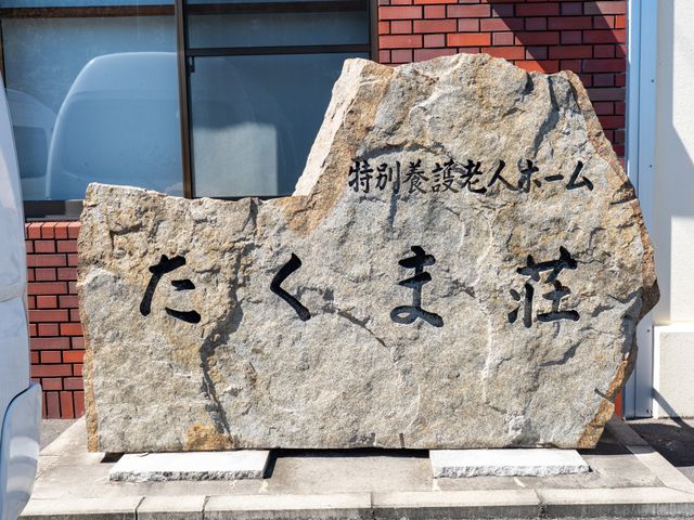 石碑の施設名外観 外観   大きな石碑に施設名が刻まれており、落ち着いた外観です。窓辺には自然光が入り、建物の様子がよく分かります。