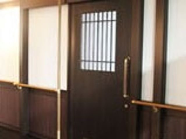 入口のドア 廊下 手すりが設置された、安全に配慮された施設の廊下です。高齢者の移動をサポートします。