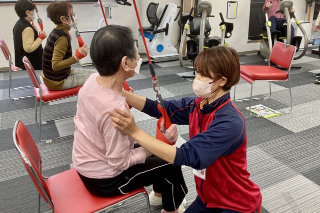 機能訓練の様子 明るい機能訓練室で、スタッフが丁寧に支援する姿が見受けられます。利用者の笑顔が印象的な、活気ある空間です。