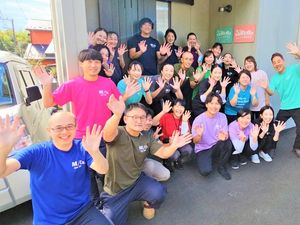 笑顔で手を振る職員の集合外観  