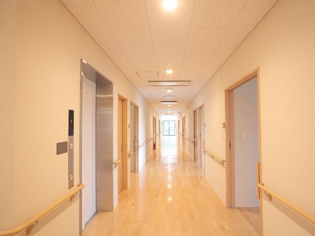 明るい清潔な廊下 廊下 床はツヤツヤで清潔感があり、手すりがついているため歩行時の安全が確保されています。廊下の端には窓から自然光が差し込み、心地よい環境で仕事ができる空間です。