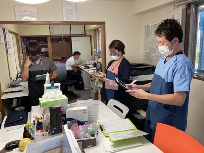 スタッフと共に打ち合わせ室