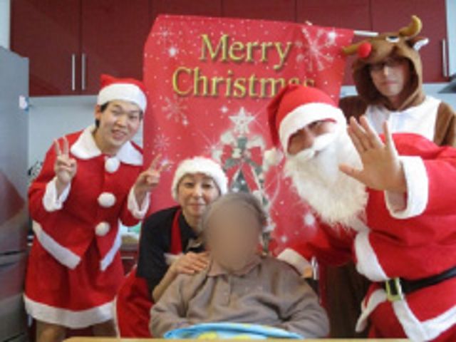 クリスマス集会の様子 多目的室 楽しいクリスマスの集会です。スタッフがサンタクロースの衣装で利用者と交流しています。