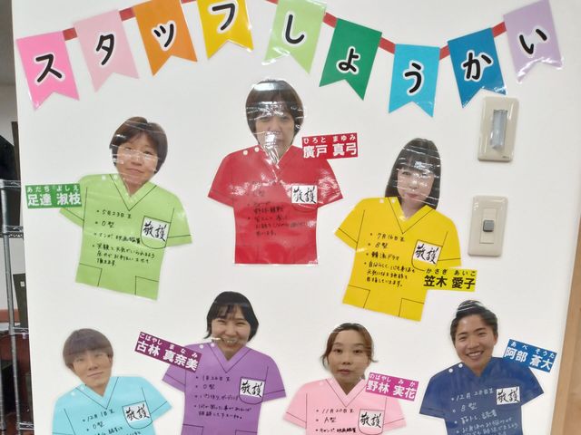 スタッフ紹介掲示物 掲示物   色分けされたユニフォーム型の掲示物に、スタッフの顔写真と名前が並んでいます。働く人の雰囲気が伝わり、職場の様子を知りやすいです。