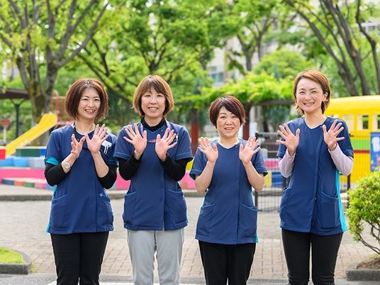 笑顔のスタッフ4人が並ぶ庭  