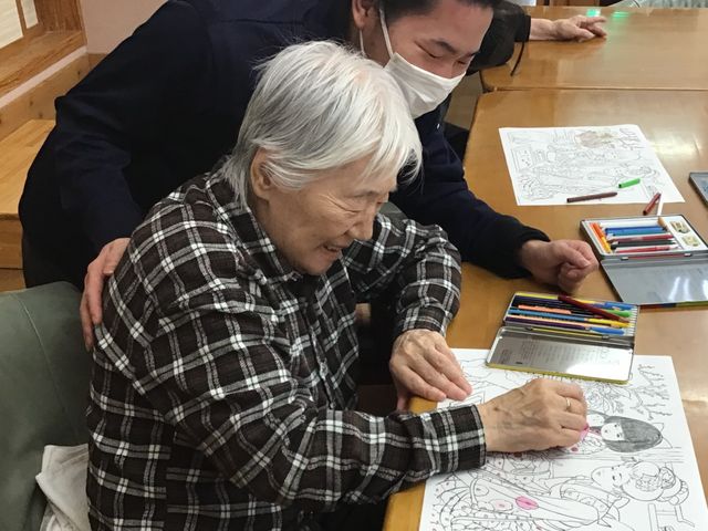 楽しむ高齢者と支援するスタッフ 多目的室 心温まる光景が広がる場での支援。スタッフは高齢者のそばで寄り添い、共に楽しむ時間を大切にしています。