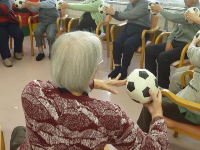 体操をする人たちの部屋 機能訓練室 自然光が差し込む空間で、利用者が楽しみながらボールを使った体操をしています。