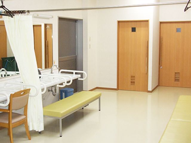 ゆったり居室 居室 広々とした居室には、手すり付きの休憩ベンチや日用品が置かれた床の低い棚があり、安全かつ快適な日々をお過ごしいただけます。