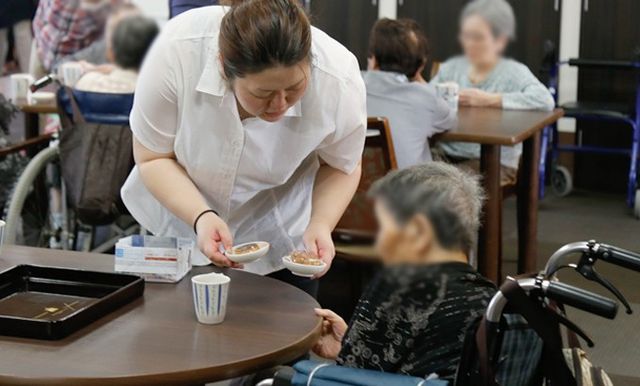 コーヒー提供の様子 ダイニングルーム 職員が入居者に飲み物を提供する温かい交流の場です。落ち着いた時間を過ごせます。