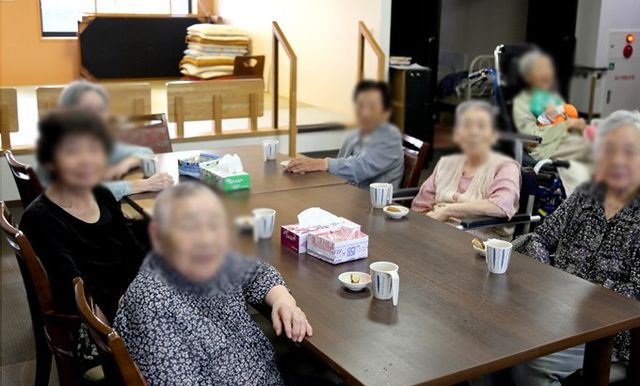 笑顔の高齢者とテーブル ラウンジ 自然な光が差し込むラウンジで、リラックスした雰囲気の中、高齢者の方が歓談を楽しんでいます。