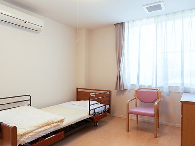 広々とした居室 居室   明るい自然光が入る居室で、落ち着いた環境が整っています。ベッドと椅子が配置されています。