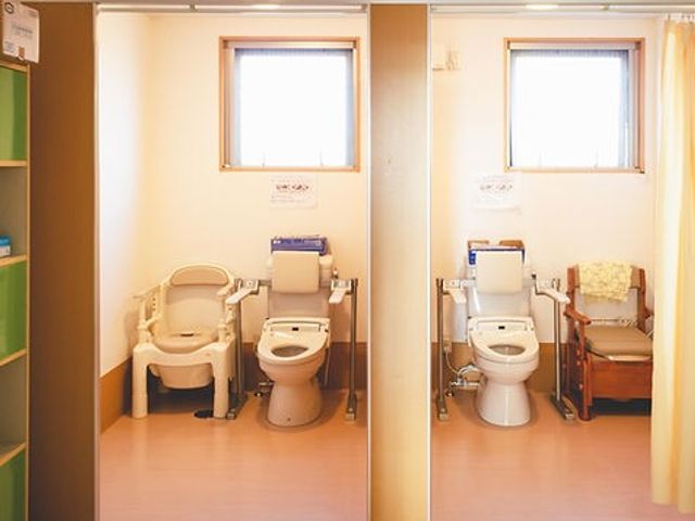 2つのトイレと椅子 トイレ 自然光が差し込む明るい環境のトイレには、手すり付きの椅子が用意されており、安心して利用できます。