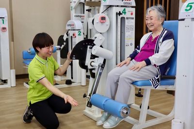 笑顔の高齢女性とスタッフ、椅子