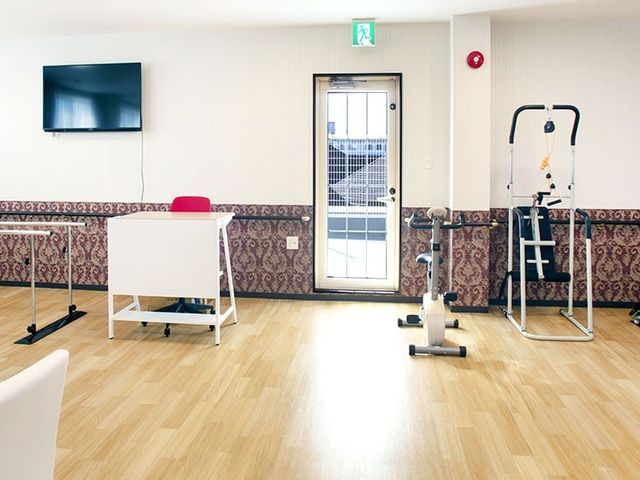 運動器具と机のある部屋 機能訓練室 運動器具が揃った明るい空間です。リハビリや日常のトレーニングに最適な設備があります。