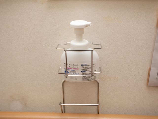 手指消毒液ボトルとそのホルダー 消毒液 衛生管理に配慮した設備が整っており、清潔感を保つための手指消毒液が設置されています。