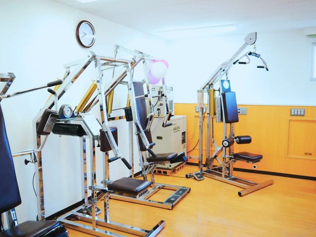 機能訓練室の器具 機能訓練室   機能訓練用の器具が並ぶ、明るく清潔感のある空間です。壁に時計があり、落ち着いて運動しやすい雰囲気です。