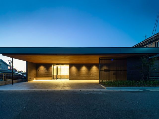 モダンな建物のエントランス 落ち着いた色合いのエントランスは、暖かい光で包まれており、訪れる人々を優しく迎え入れます。夕暮れ時には特に穏やかな雰囲気があります。