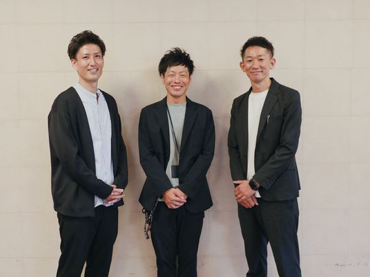 笑顔の男性3人が並ぶロビー  