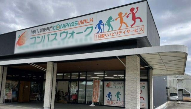 看板前の建物 看板 歩行訓練に特化したデイサービスです。明るい看板が目印になっています。
