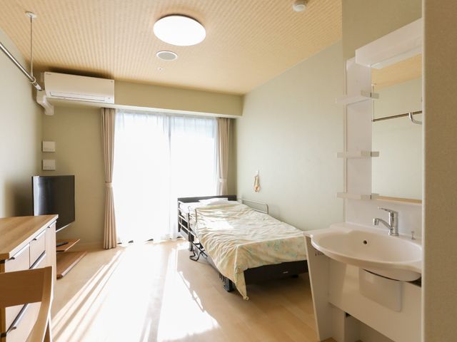 明るい居室の一角 居室 採光豊かな居室には、生活に必要な設備が整えられており、快適なプライベート空間をご提供します。デスクや洗面台も備え、独立した生活を支援しています。
