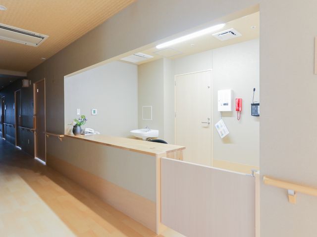 廊下に面した洗面台 受付 ゆったりとした廊下に備え付けられた洗面台があり、清潔で機能的な空間が保たれています。廊下の手すりは安全な移動をサポートします。