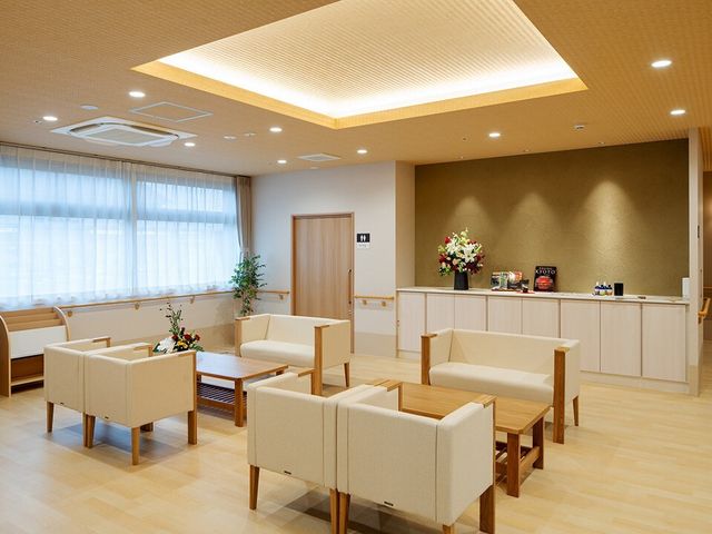 暖色系照明の応接室 エントランス ゆったりとしたソファが並ぶ安らぎのスペースです。温かみのある照明が心地よい雰囲気を演出しており、訪れる方々の憩いの場になっています。