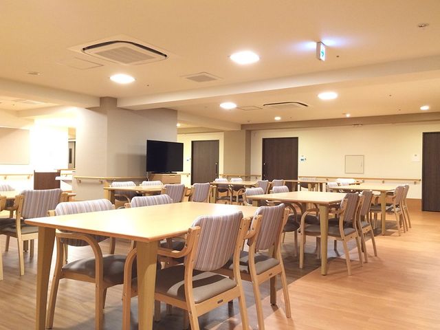 明るい食堂 食堂   広々とした食堂で、複数のテーブルと椅子がゆったり配置されています。明るい照明の下、食事や会話がしやすそうな空間です。