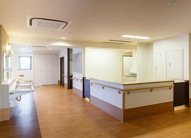 ケア施設の広い廊下 共有スペース２ 広々とした廊下には手すりが備えられ、バリアフリー設計が施されております。安全かつゆったりとした移動が可能です。