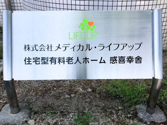 看板のクローズアップ 館銘板 明るい色合いの看板が入口を飾る場所です。訪れる方々に、心地よい歓迎の気持ちを伝えています。