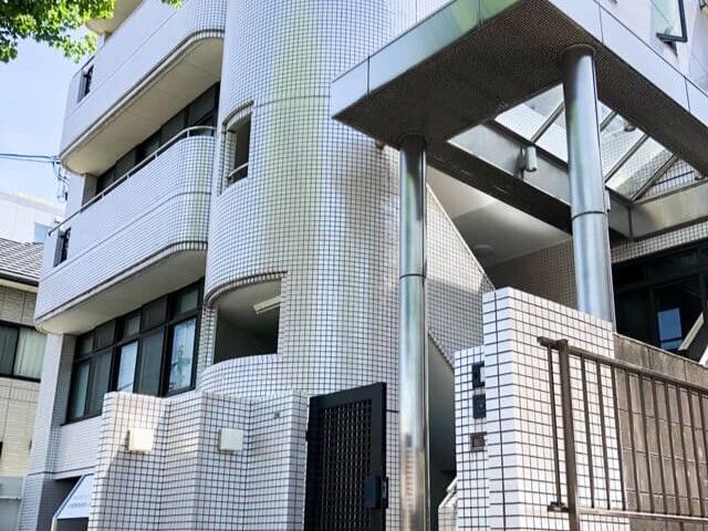 白いタイルの建物エントランス 外観 清潔感のある白いタイル仕上げの入り口は、明るく開放的であり、来訪される方を暖かく迎えます。