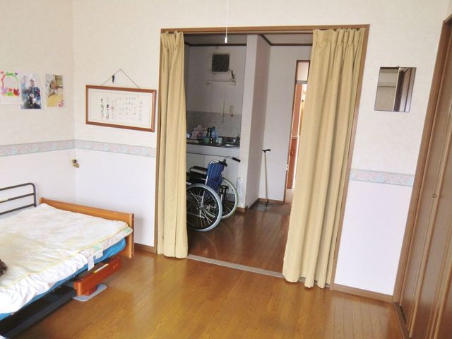 居室にあるベッドと車椅子 居室 明るく広々とした居室です。ベッド横には移動に便利な車椅子が配備され、快適な生活環境が整っています。