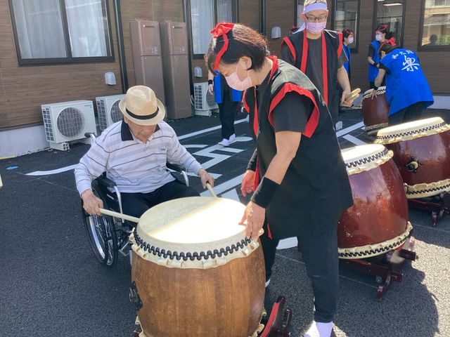 太鼓イベントを支える職員 中庭 スタッフと入居者が共に楽しむ文化イベントを支え、温かいコミュニティを築くやりがいのある仕事です。