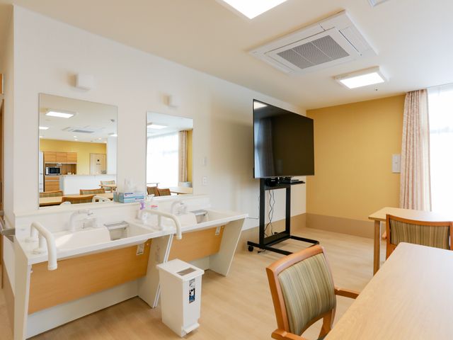 広々とした明るい居室 洗面台 広々とした居室には洗面台とテレビが完備され、快適に過ごすことができそうです。窓からは柔らかな自然光が差し込み、穏やかな雰囲気を醸し出しています。
