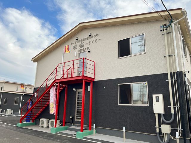 施設の外観の正面 外観１ 赤い階段が印象的なモダンな建物です。明るく清潔感があり、日々の業務で快適な環境が広がっています。