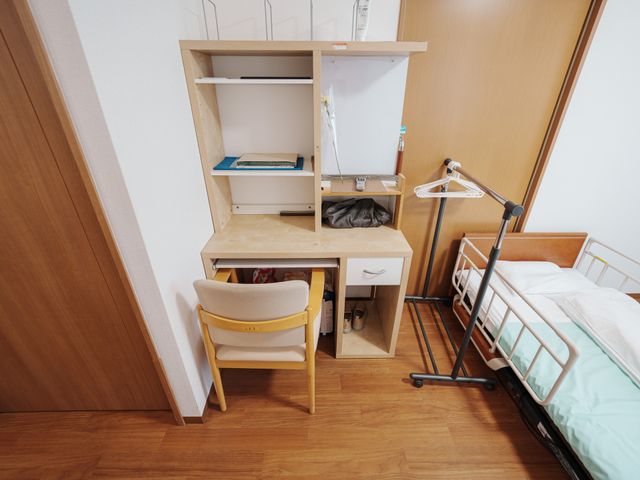 整理整頓された居室 居室 清潔感あふれる個室です。必要な物品をまとめて収納できる棚と、快適な睡眠をサポートするベッドを備えています。