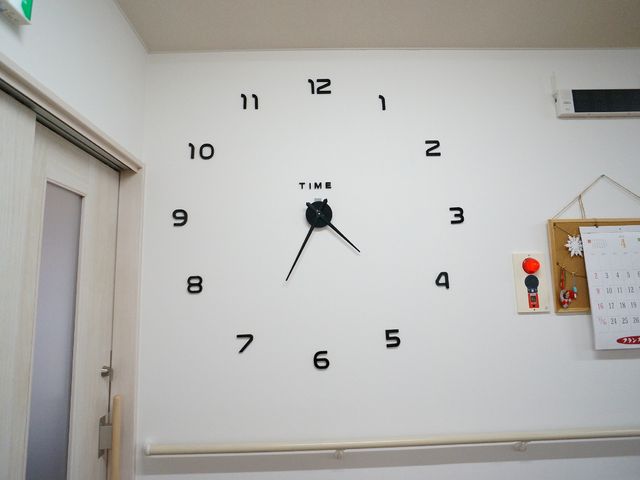 壁時計とカレンダーの廊下 共有スペース 壁に大きな時計があり、時刻が一目で分かる明るい通路です。日々のスケジュールを確認できるカレンダーも備え付けております。